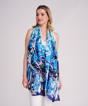 Blue oblong scarf featuring a vibrant abstract floral print in rich blue tones for a striking seasonal statement. Crafted from soft, lightweight satin silk with a smooth drape and polished hemline edging for a refined finish. Suitable for versatile styling as a neck scarf, shawl, or wrap.
