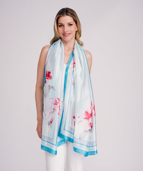 Turquoise oblong scarf featuring a vibrant abstract floral print with pink tones for a bold seasonal statement. Crafted from soft, lightweight satin silk with a smooth drape and polished hemline edging for a refined finish. Suitable for versatile styling as a neck scarf, shawl, or wrap.