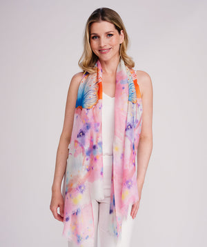 Pink oblong scarf featuring a bold butterfly print in rainbow hues for a vibrant seasonal statement. Crafted from soft, lightweight chiffon with a flowy drape and raw edge hemline for a modern finish. Suitable for versatile styling as a neck scarf, shawl, or wrap.
