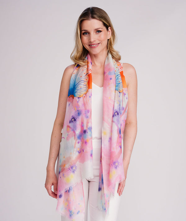 Pink oblong scarf featuring a bold butterfly print in rainbow hues for a vibrant seasonal statement. Crafted from soft, lightweight chiffon with a flowy drape and raw edge hemline for a modern finish. Suitable for versatile styling as a neck scarf, shawl, or wrap.