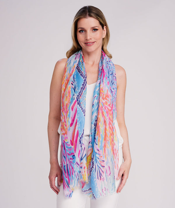 Blue oblong scarf featuring a vibrant multi-tone abstract print for a bold seasonal statement. Crafted from soft, lightweight fabric with an airy drape and delicate edging for a modern finish. Suitable for versatile styling as a neck scarf, shawl, or wrap.